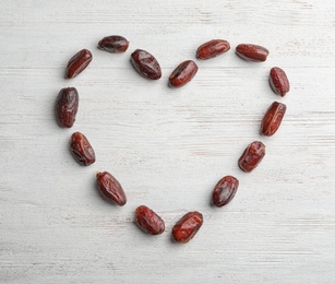 Frame made of sweet dried date fruits on wooden background, top view with space for text