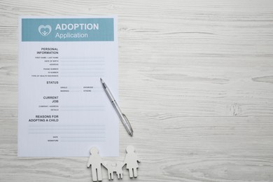Photo of Adoption application, family figure and pen on white wooden table, flat lay. Space for text