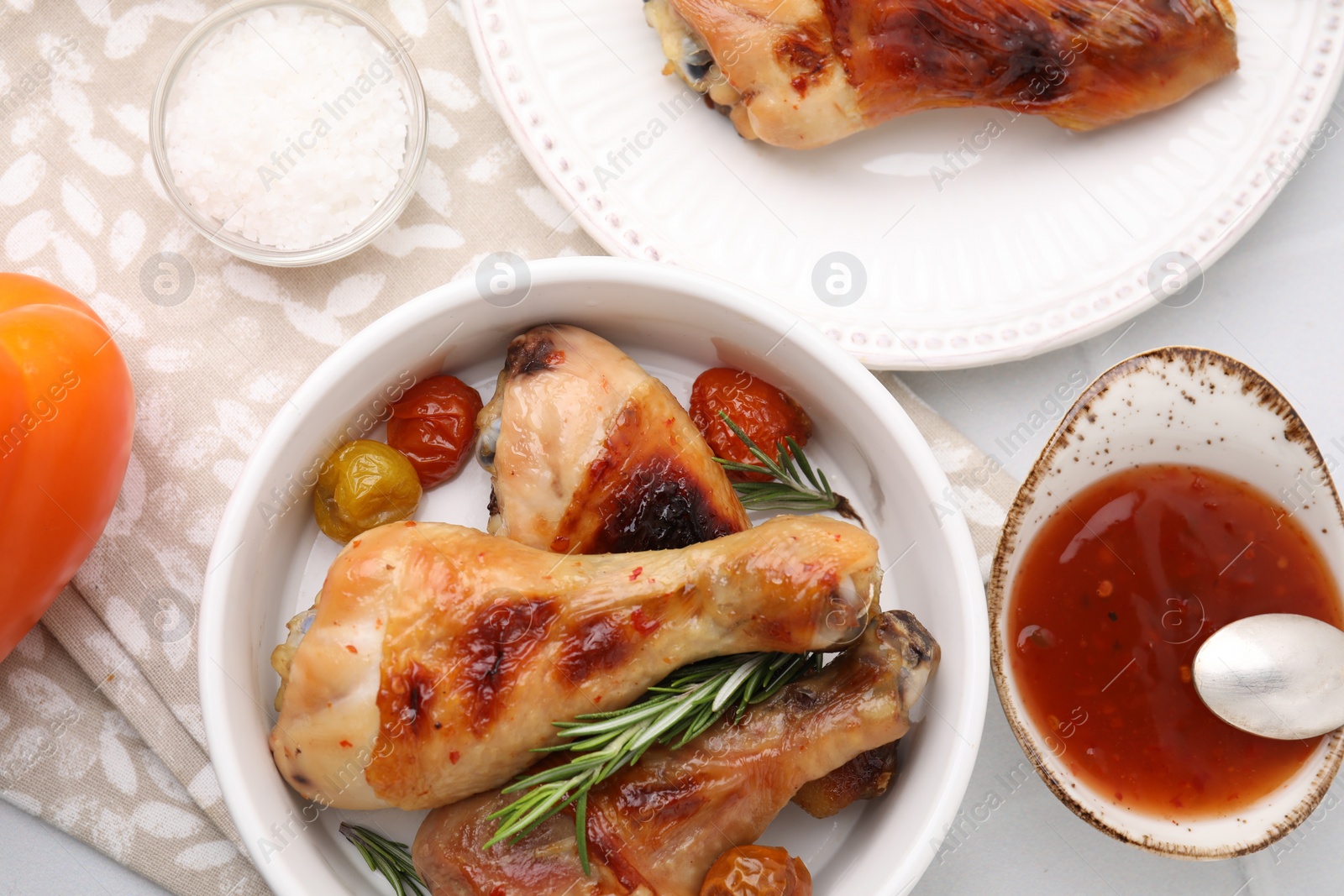 Photo of Marinade, roasted chicken drumsticks, rosemary and tomatoes on white table, flat lay