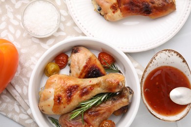 Marinade, roasted chicken drumsticks, rosemary and tomatoes on white table, flat lay