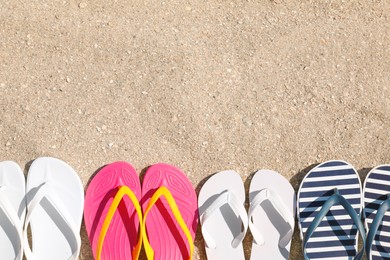 Many different flip flops on sand, flat lay. Space for text