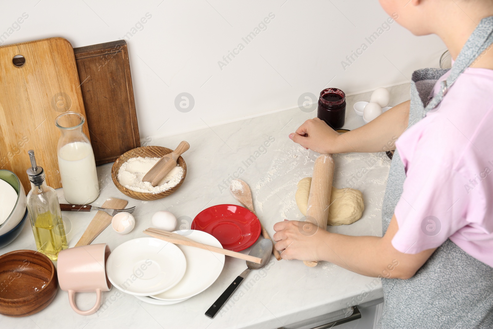 Photo of Woman cooking at messy countertop in kitchen, closeup. Many dishware, utensils and food leftovers on table