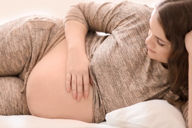 Photo of Young pregnant woman lying on bed at home