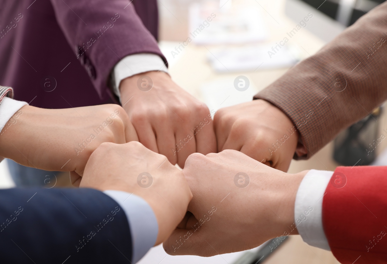 Photo of Women holding fists together over table indoors, closeup