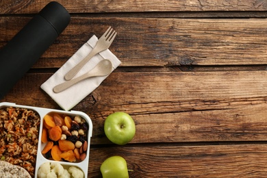 Photo of Flat lay composition with thermos and lunch box on wooden background, space for text