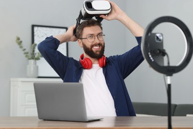 Smiling technology blogger recording video review about virtual reality headset at home