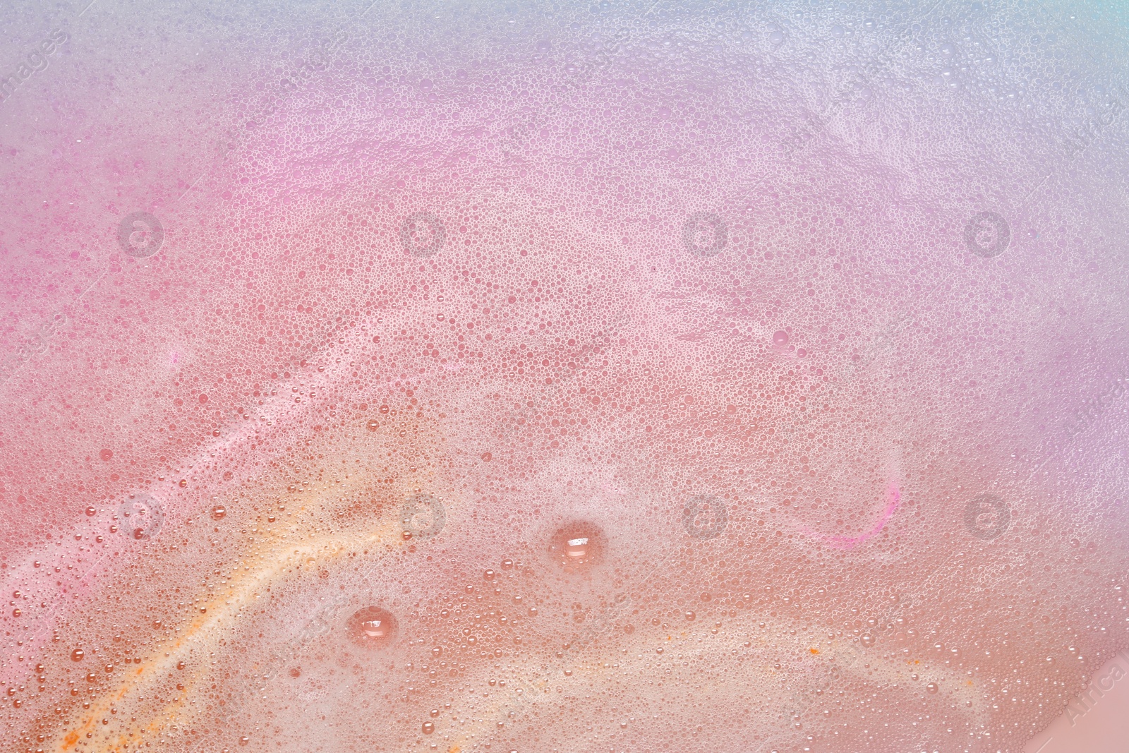 Photo of Colorful foam after dissolving bath bomb in water, closeup