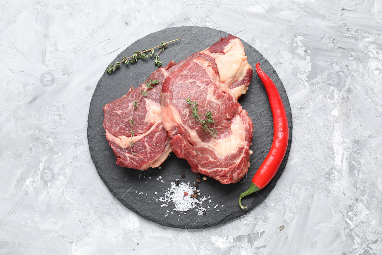 Photo of Fresh raw beef cut with different spices on light grey textured table, top view