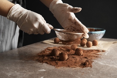 Photo of Woman preparing tasty chocolate truffles at table, closeup