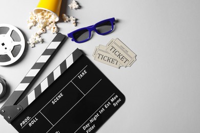Photo of Flat lay composition with clapperboard, film reel and 3D glasses on grey background, space for text