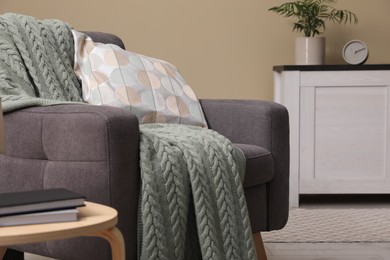 Photo of Living room interior with comfortable grey armchair, pillow and plaid