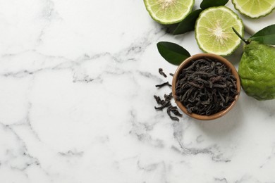 Photo of Dry bergamot tea leaves and fresh fruits on white marble table, flat lay. Space for text