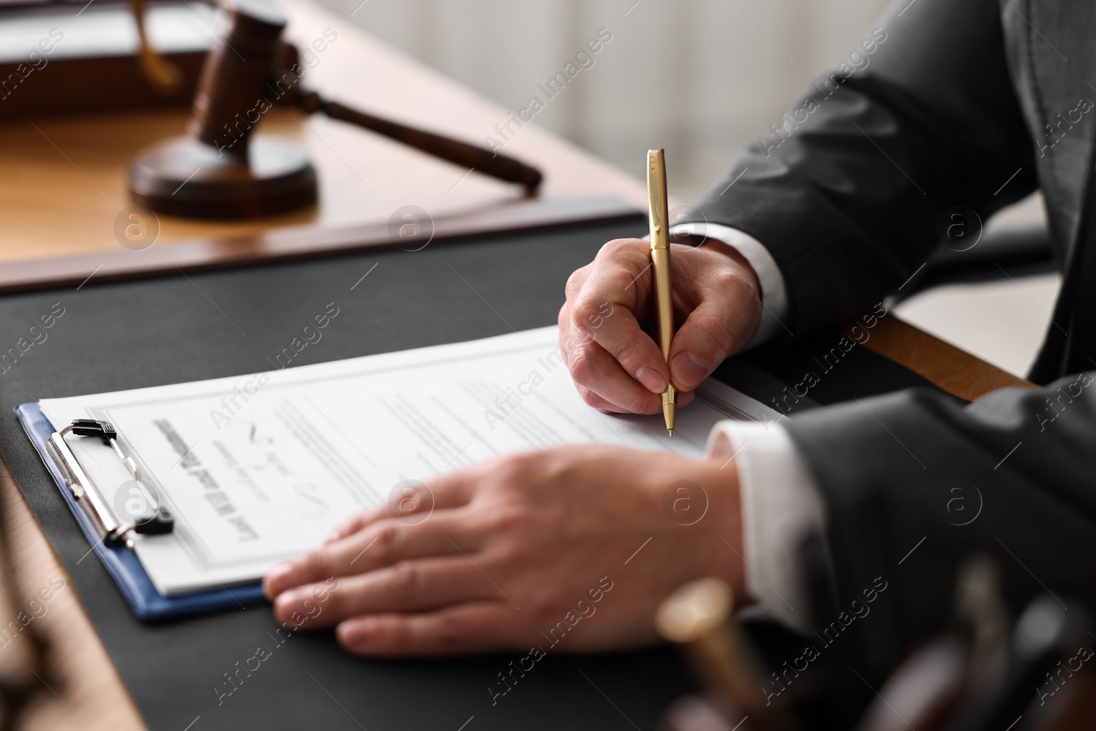 Photo of Notary writing notes at wooden table in office, closeup