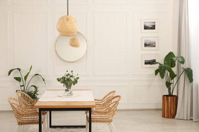 Stylish dining room with cozy furniture, mirror and plants