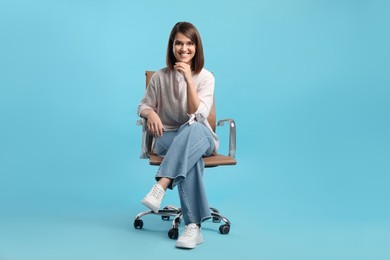 Photo of Young woman sitting in comfortable office chair on turquoise background
