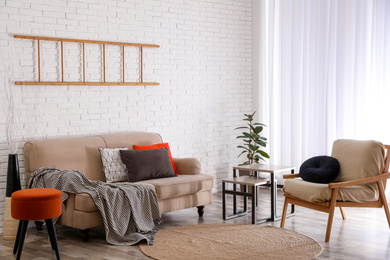 Soft pillows on sofa near white brick wall at home