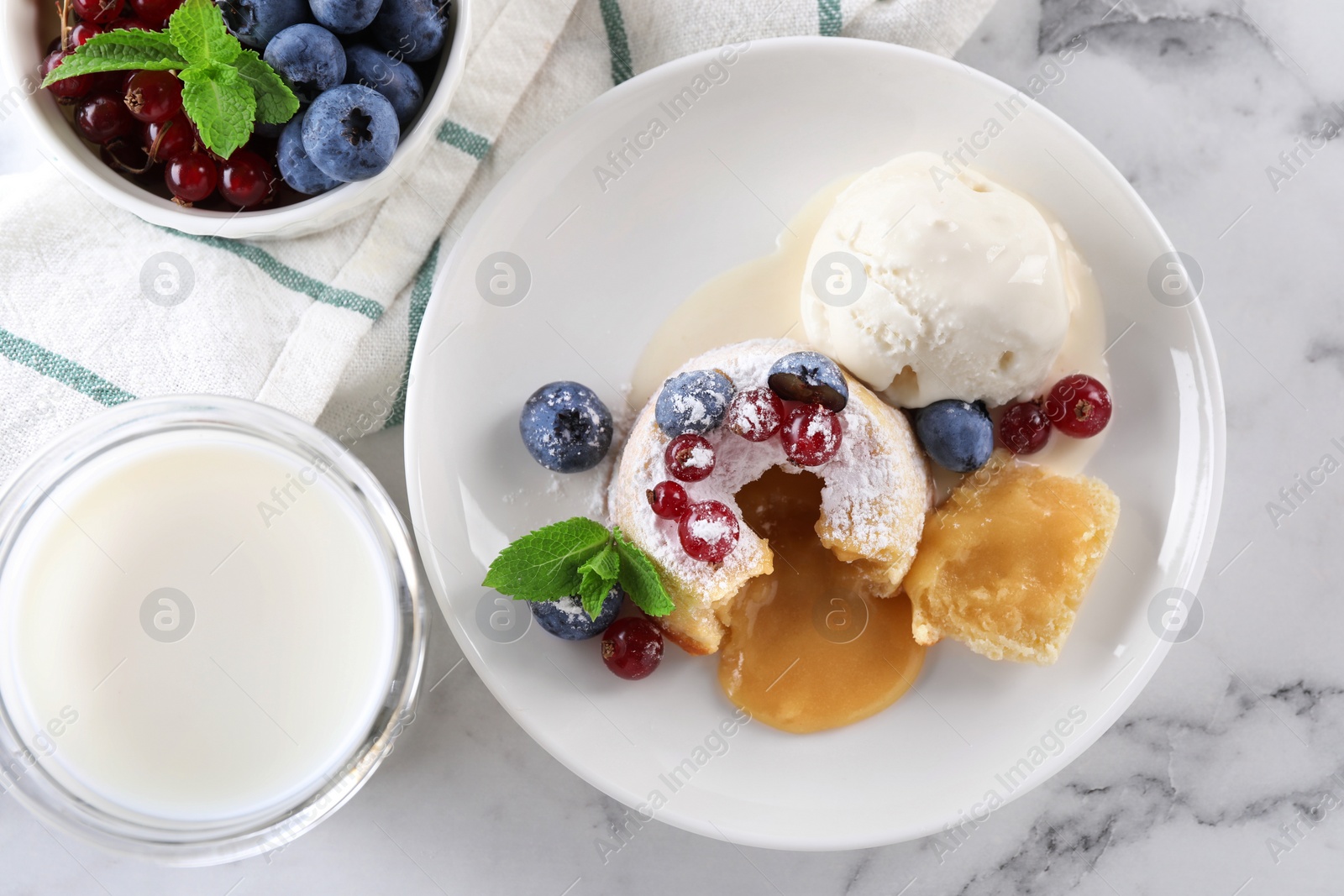 Photo of Tasty vanilla fondant with white chocolate, berries and ice cream served on white marble table, flat lay