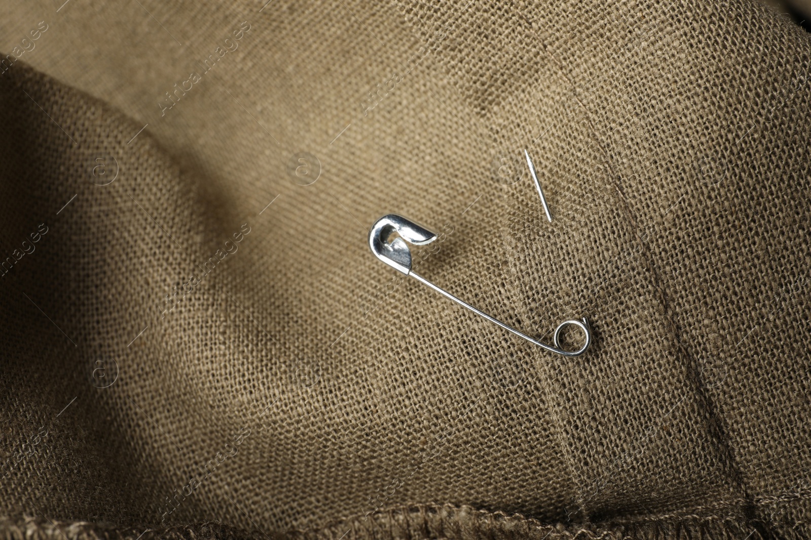 Photo of Metal safety pin on fabric, closeup view