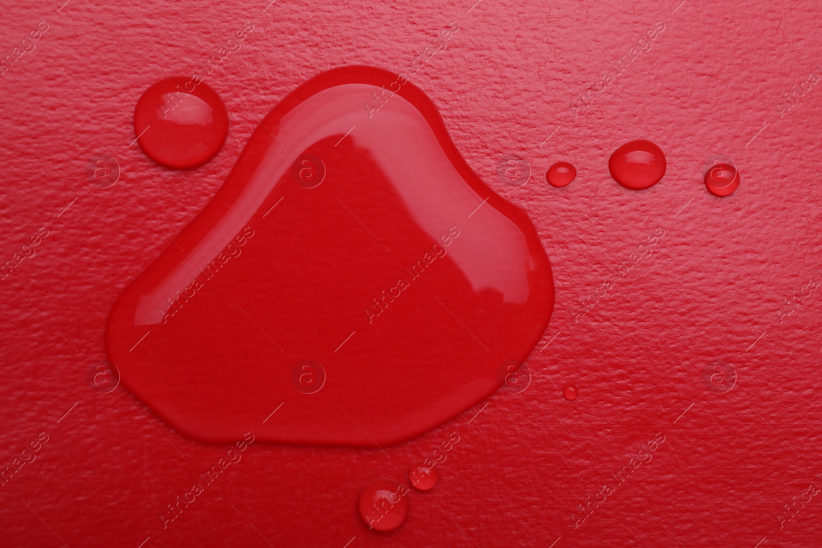 Photo of Puddle of water on red background, top view