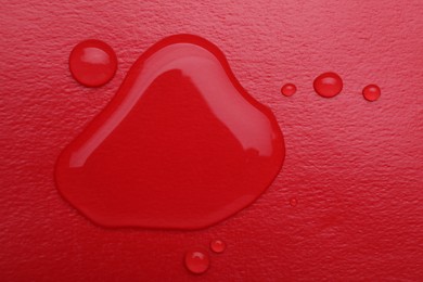 Photo of Puddle of water on red background, top view