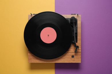 Photo of Modern turntable with vinyl record on color background, top view