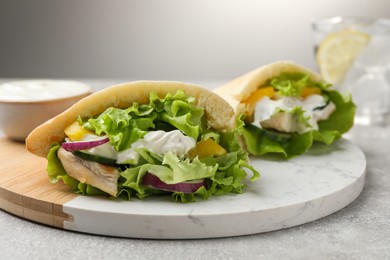 Photo of Delicious pita sandwiches with chicken breast and vegetables on light gray table, closeup