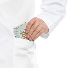 Doctor putting bribe into pocket on white background, closeup. Corruption in medicine