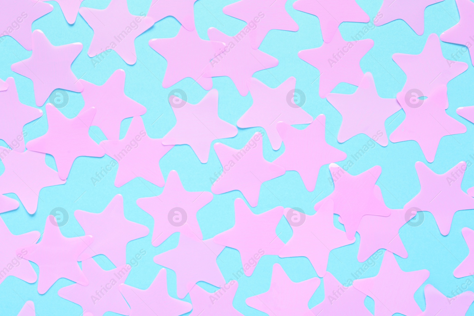 Photo of Pink star shaped confetti on light blue background, flat lay