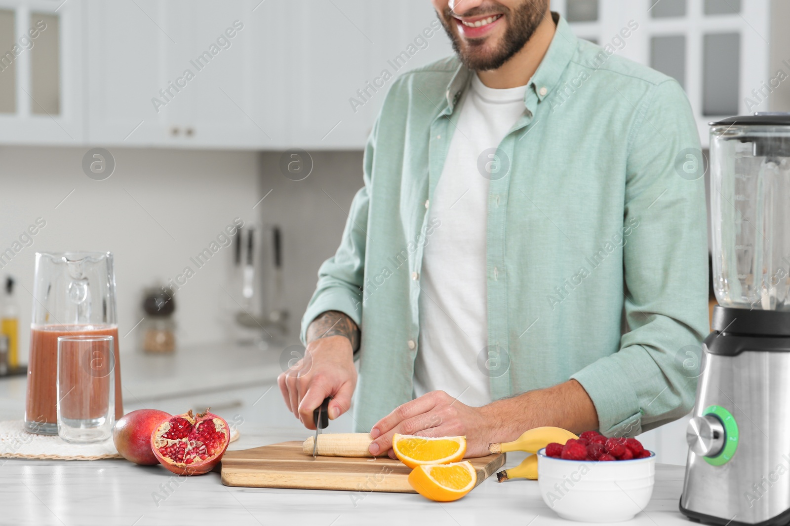 Photo of Man preparing ingredients for tasty smoothie at white marble table in kitchen, closeup