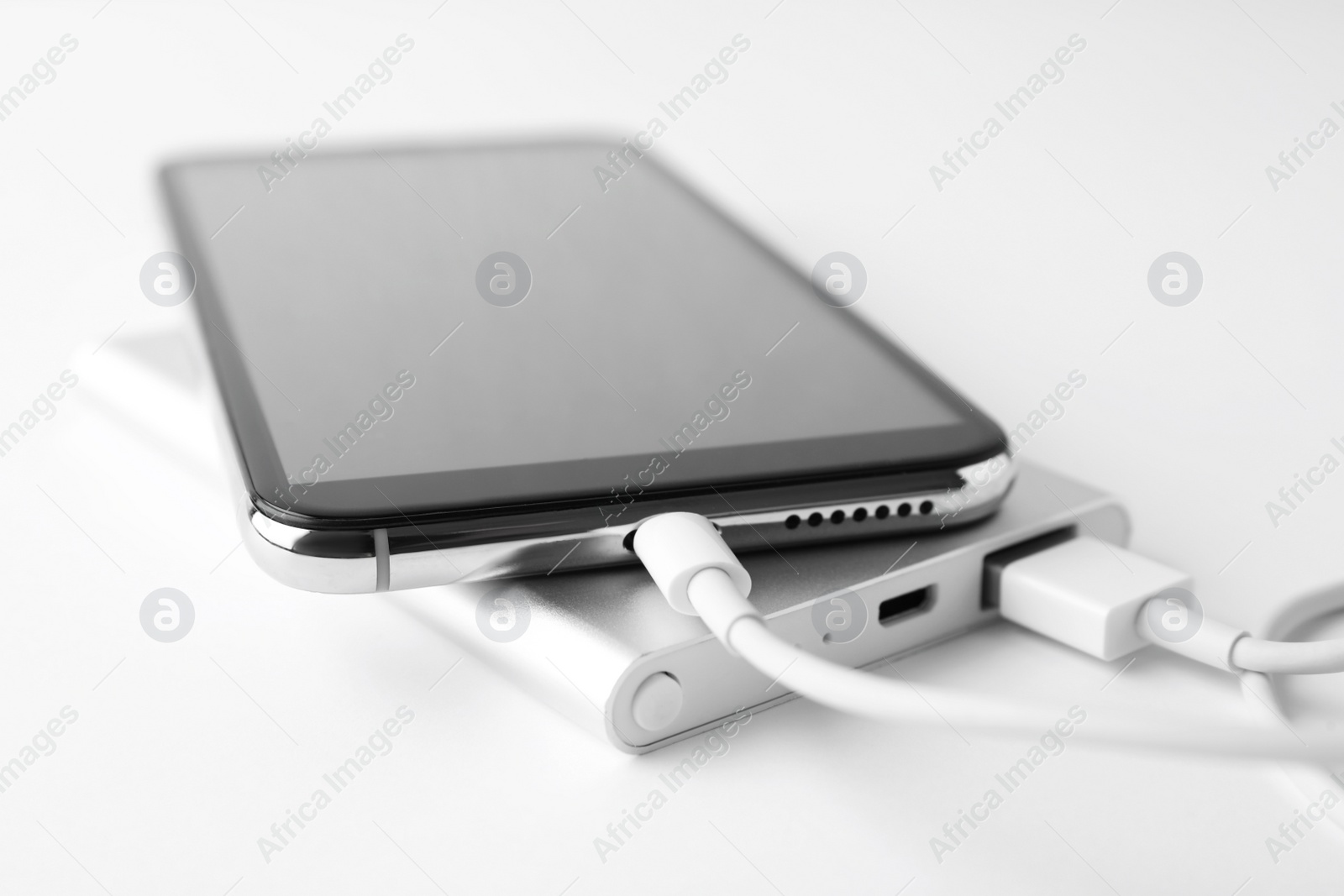 Photo of Smartphone charging with power bank on white background, closeup