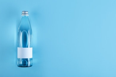 Bottle of water on color background, top view. Space for text