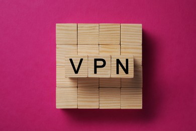 Photo of Wooden cubes with acronym VPN on crimson background, top view