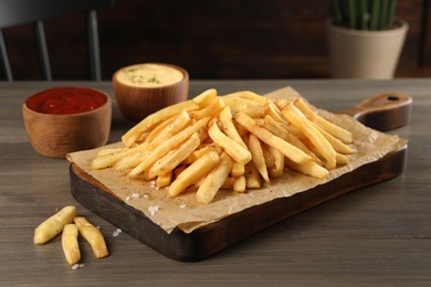 Delicious french fries served with sauces on wooden table