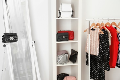 Wardrobe with stylish bags and clothes indoors. Idea for interior design