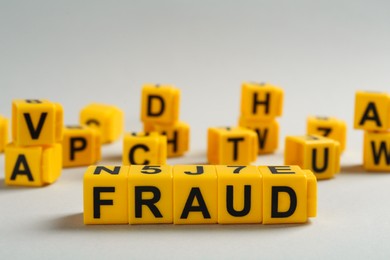 Photo of Word Fraud of yellow cubes with letters on light grey background