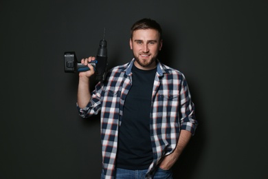 Photo of Young working man with power drill on dark background