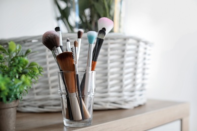 Holder with makeup brushes on table