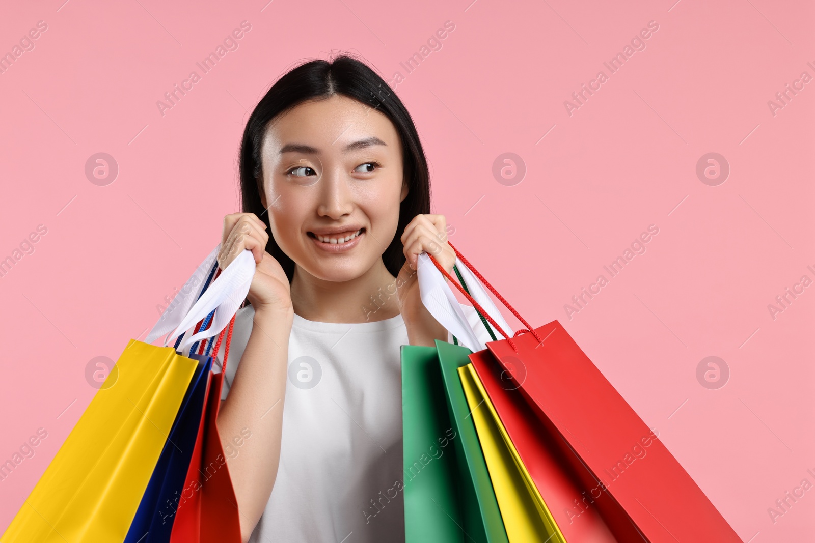 Photo of Happy woman with shopping bags on pink background. Space for text