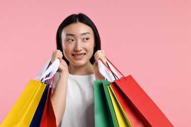 Photo of Happy woman with shopping bags on pink background. Space for text