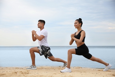 Couple doing exercise together on beach. Body training