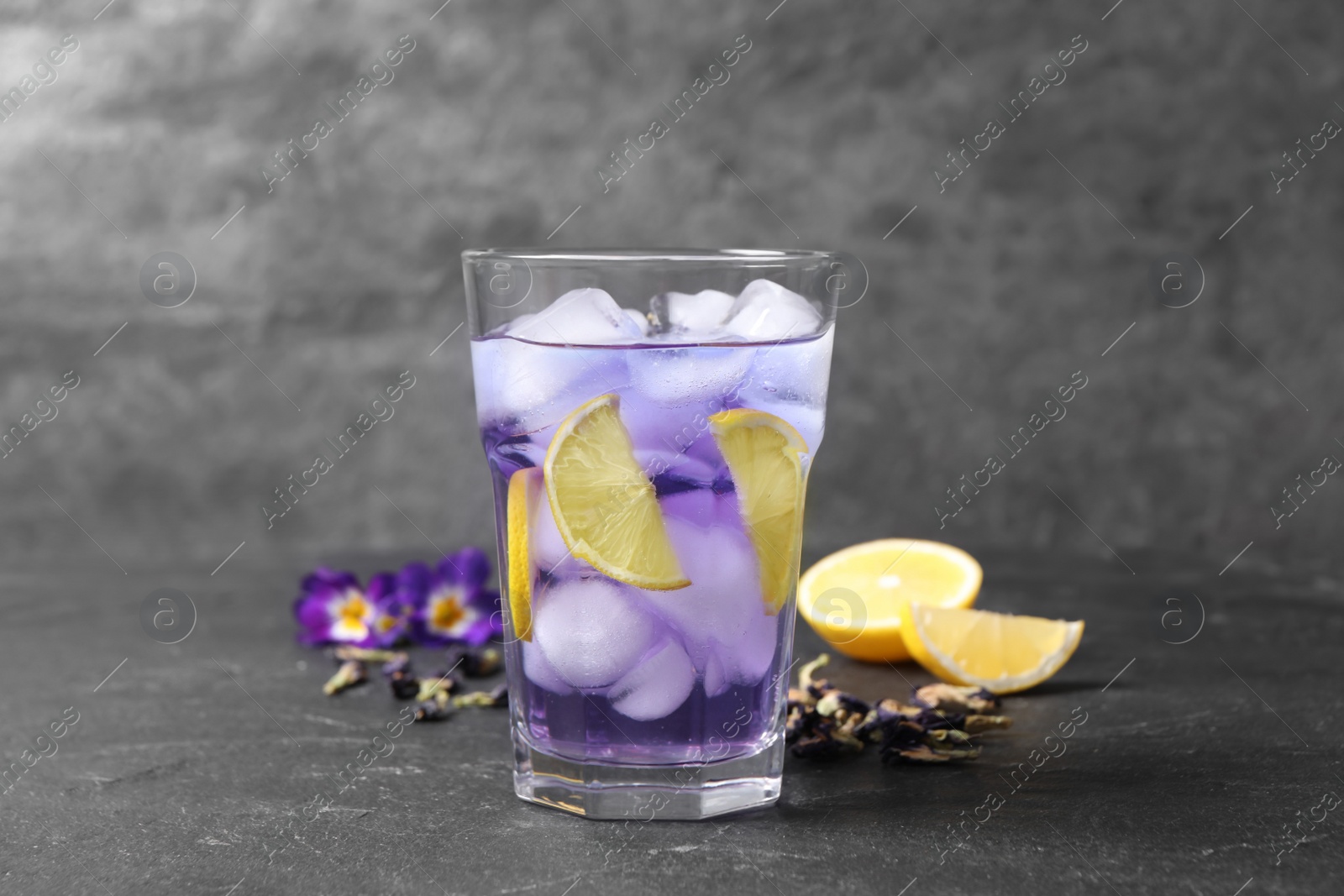 Photo of Organic blue Anchan with lemon in glass on grey table. Herbal tea