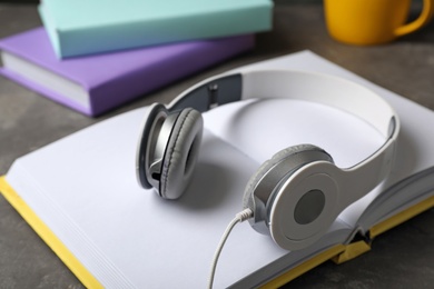 Photo of Modern headphones with hardcover book on grey table, closeup
