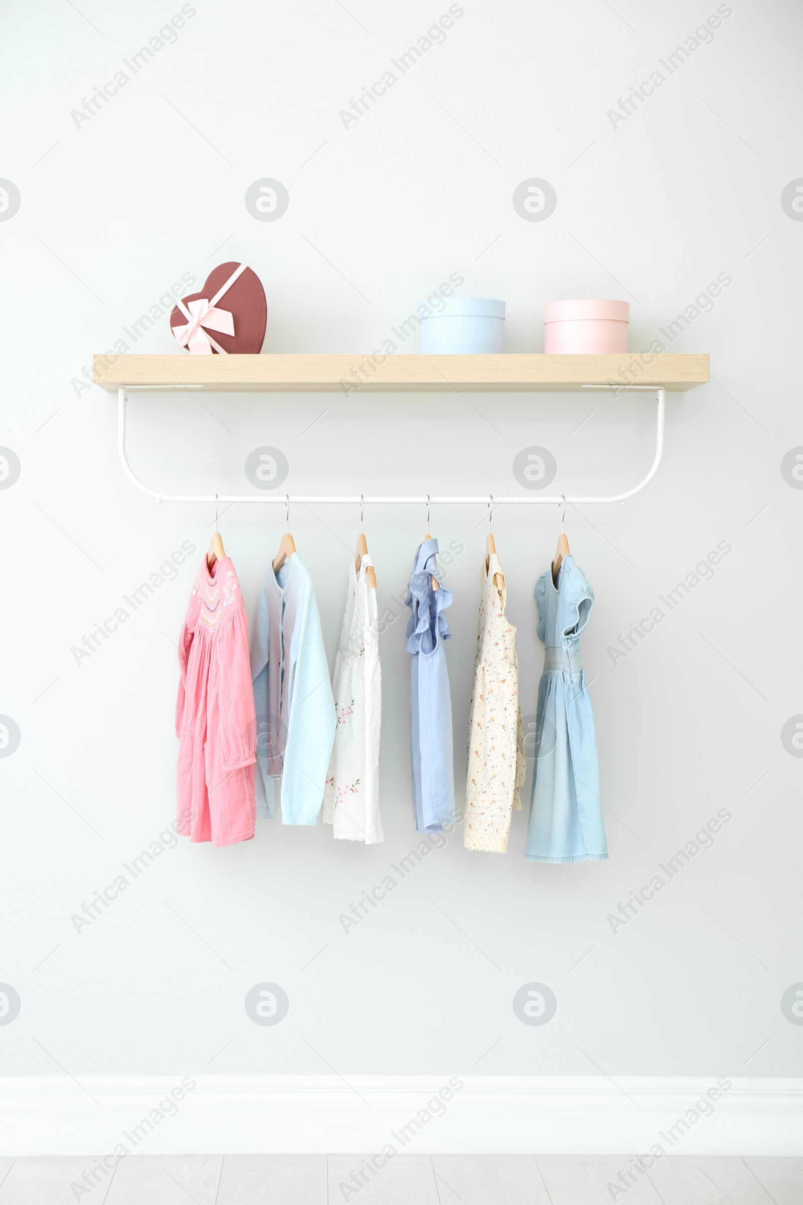 Photo of Rack with different clothes on light wall