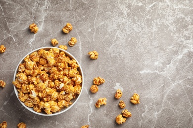 Delicious popcorn with caramel in bowl on gray background, top view