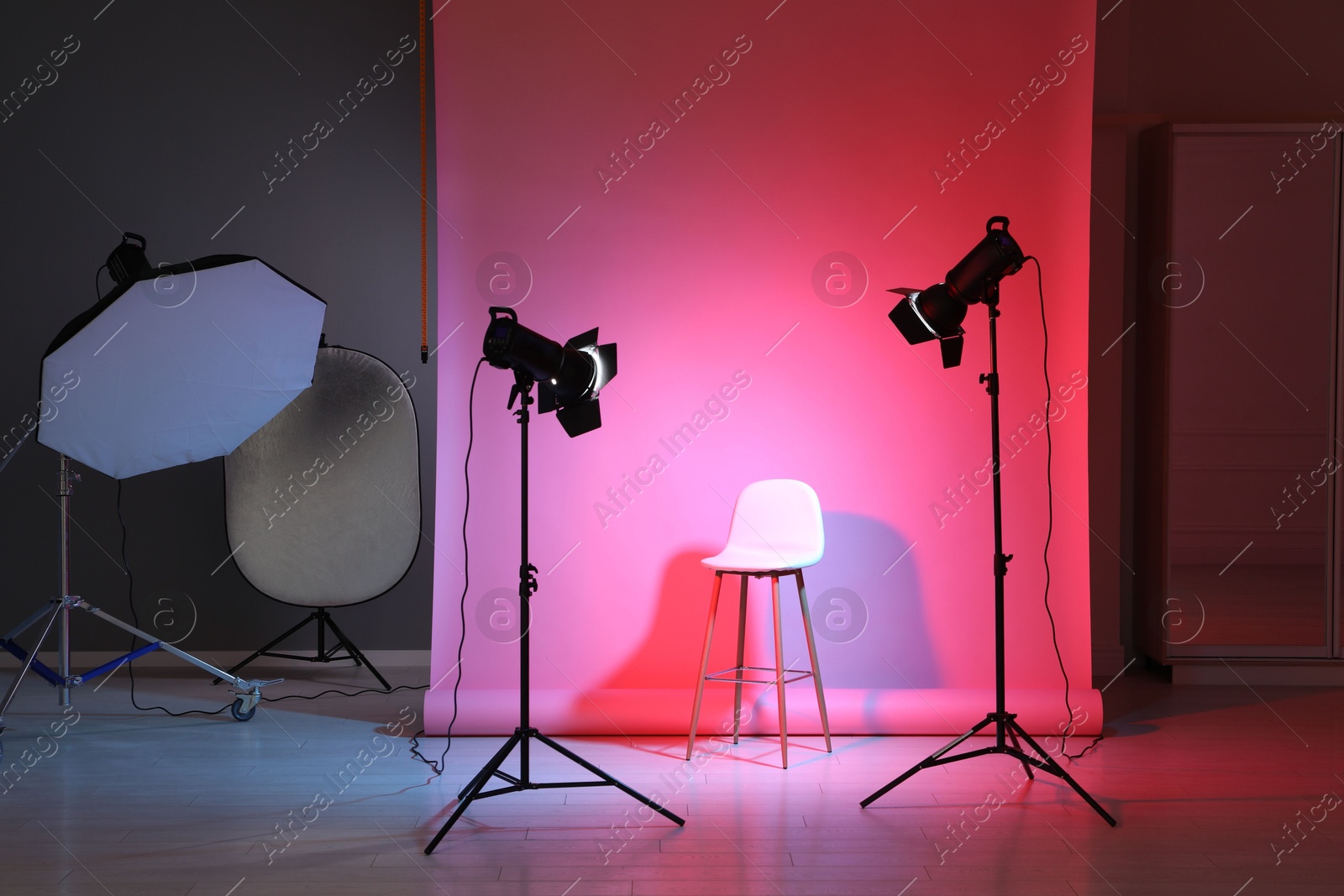 Photo of Photo background in neon lights and professional lighting equipment inside modern studio