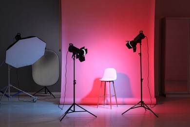 Photo of Photo background in neon lights and professional lighting equipment inside modern studio