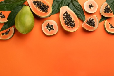 Fresh ripe papaya fruits with green leaves on orange background, flat lay. Space for text