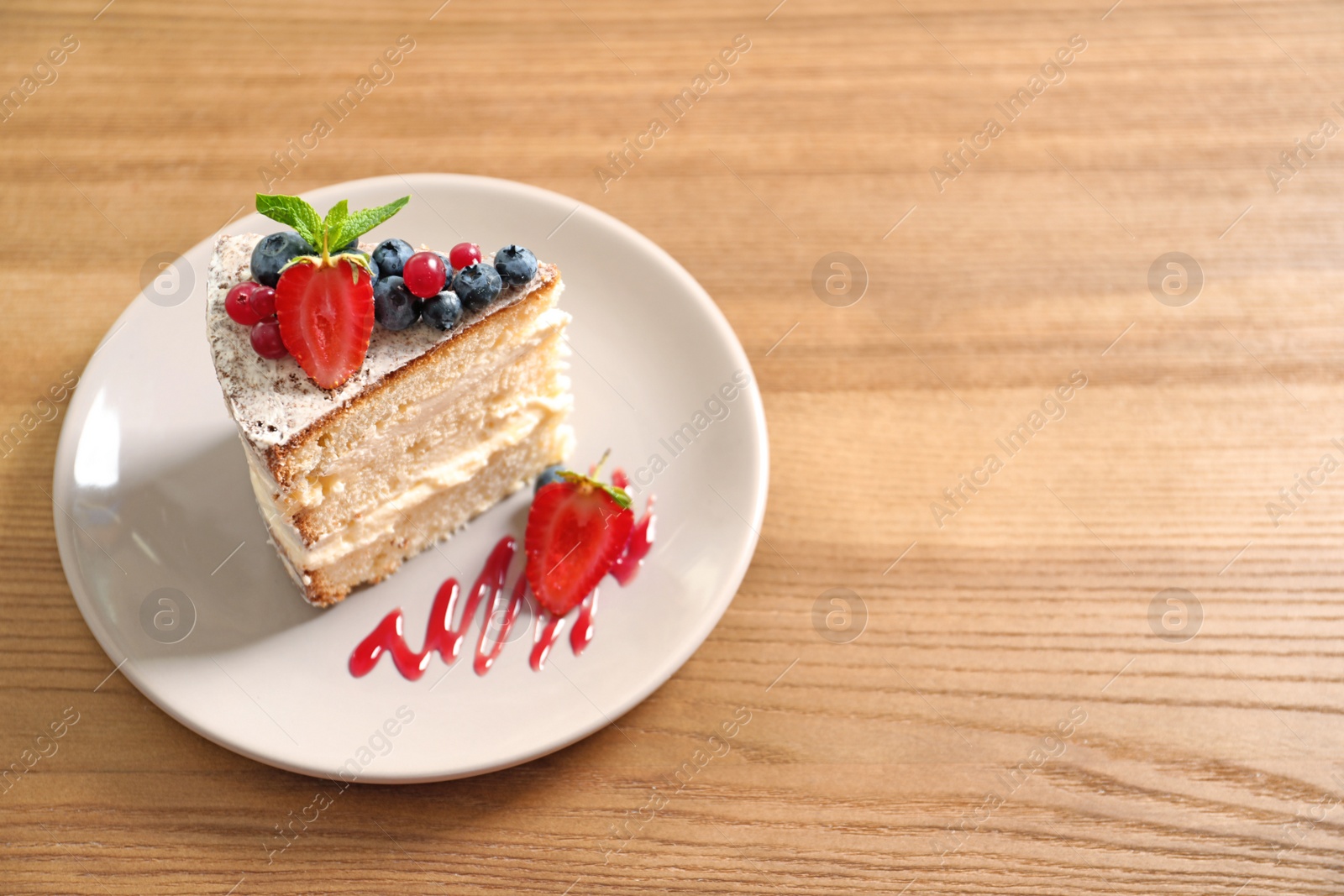 Photo of Piece of delicious homemade cake with fresh berries and space for text on wooden table