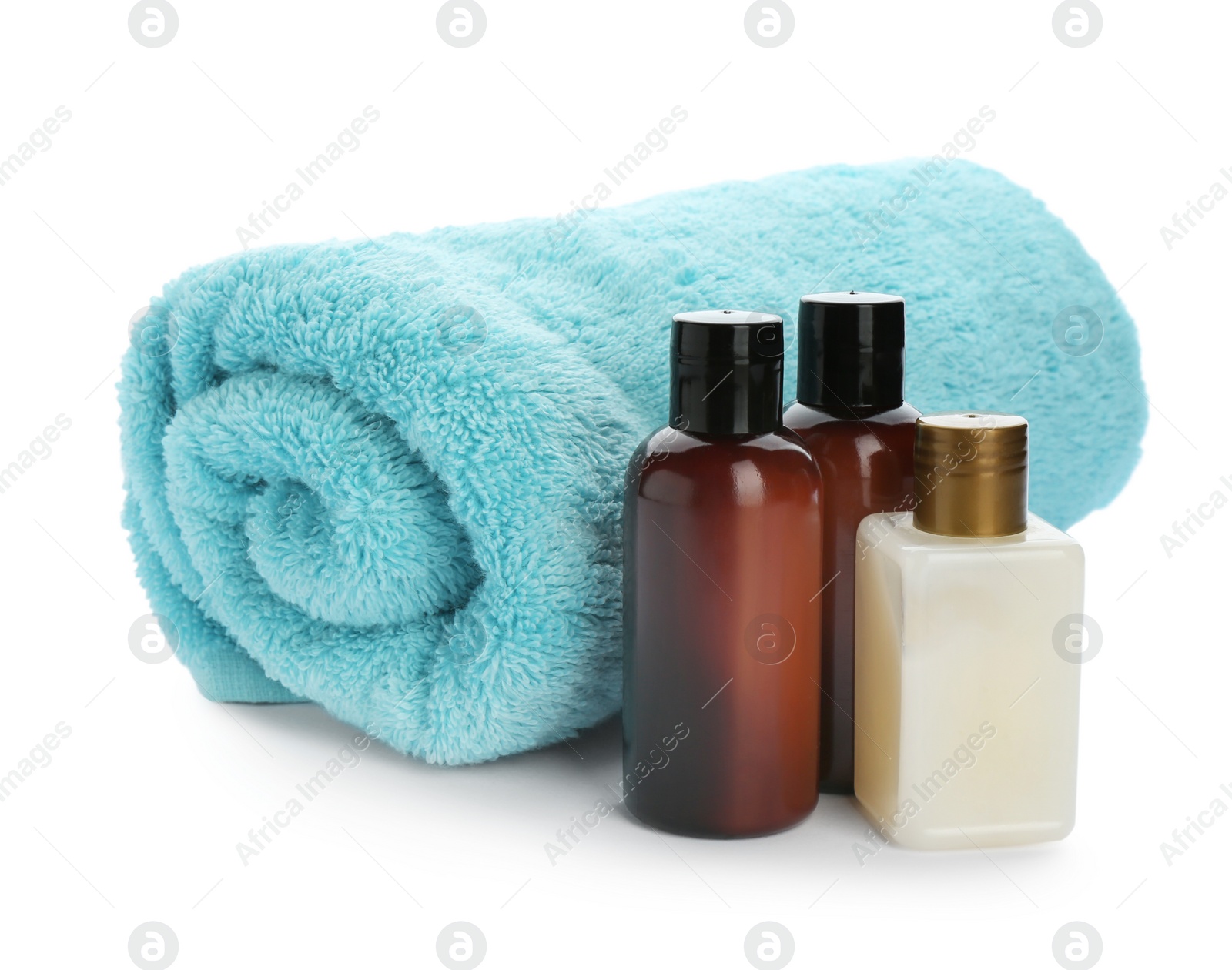 Photo of Mini bottles with cosmetic products and towel on white background. Hotel amenities