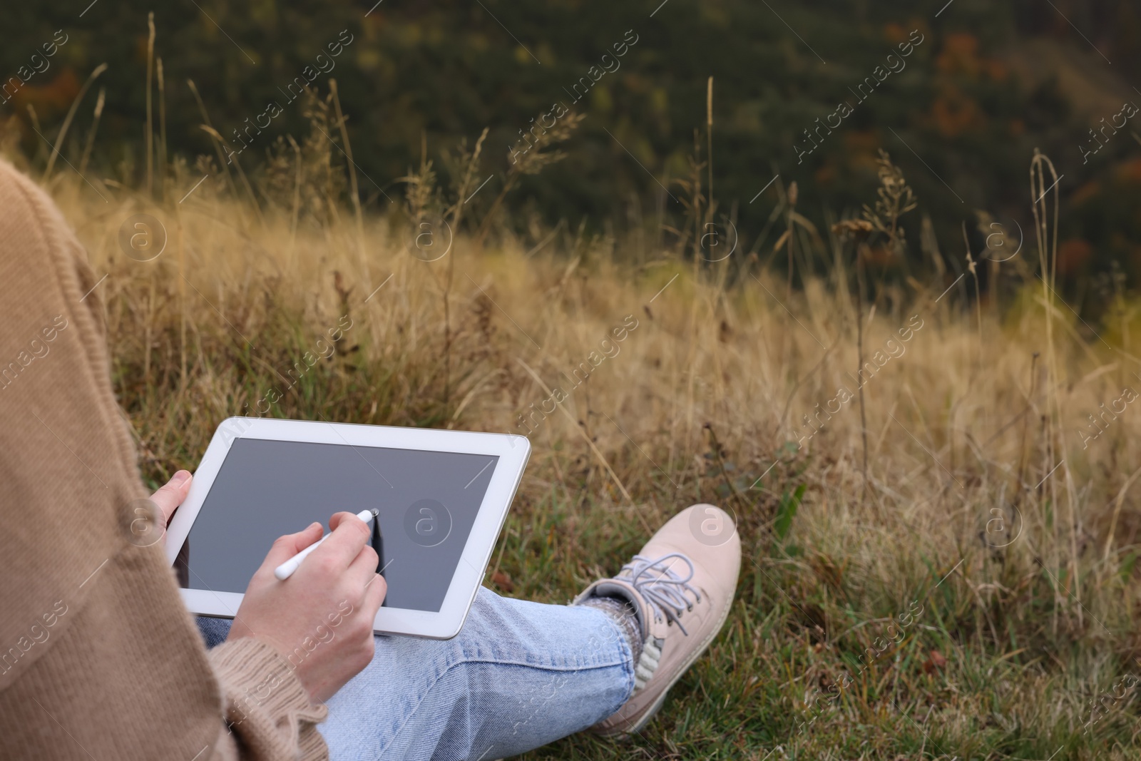 Photo of Woman using tablet for drawing outdoors, closeup